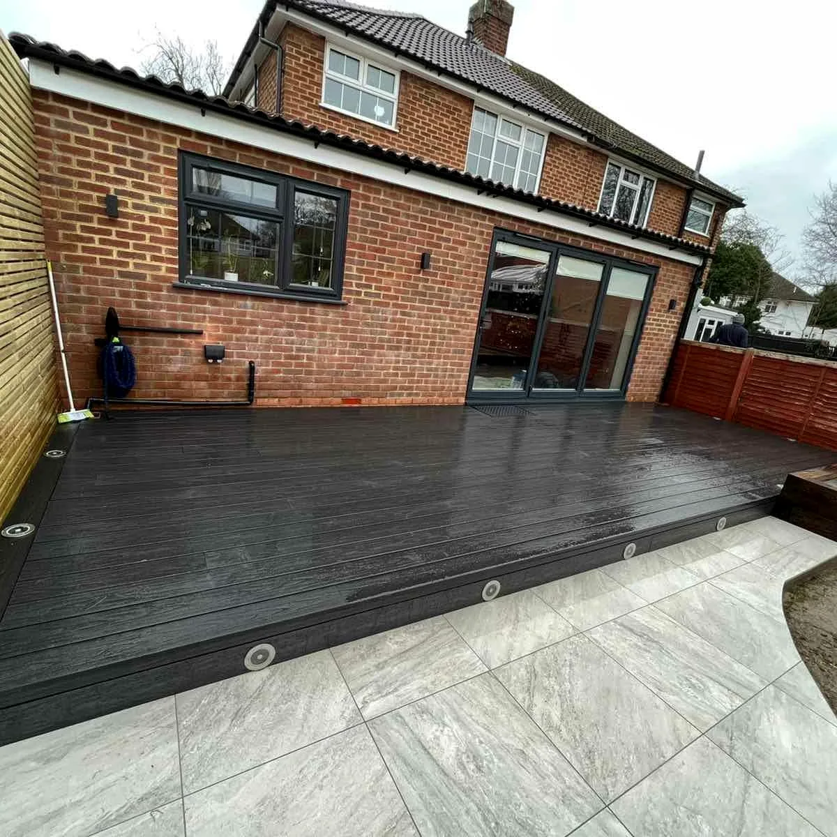 Completed garden with dark composite decking, porcelain paving and brick extension