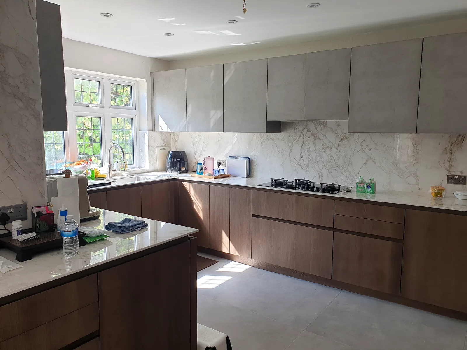 Open-plan fitted kitchen with wood cabinetry, stone worktops and gas hob