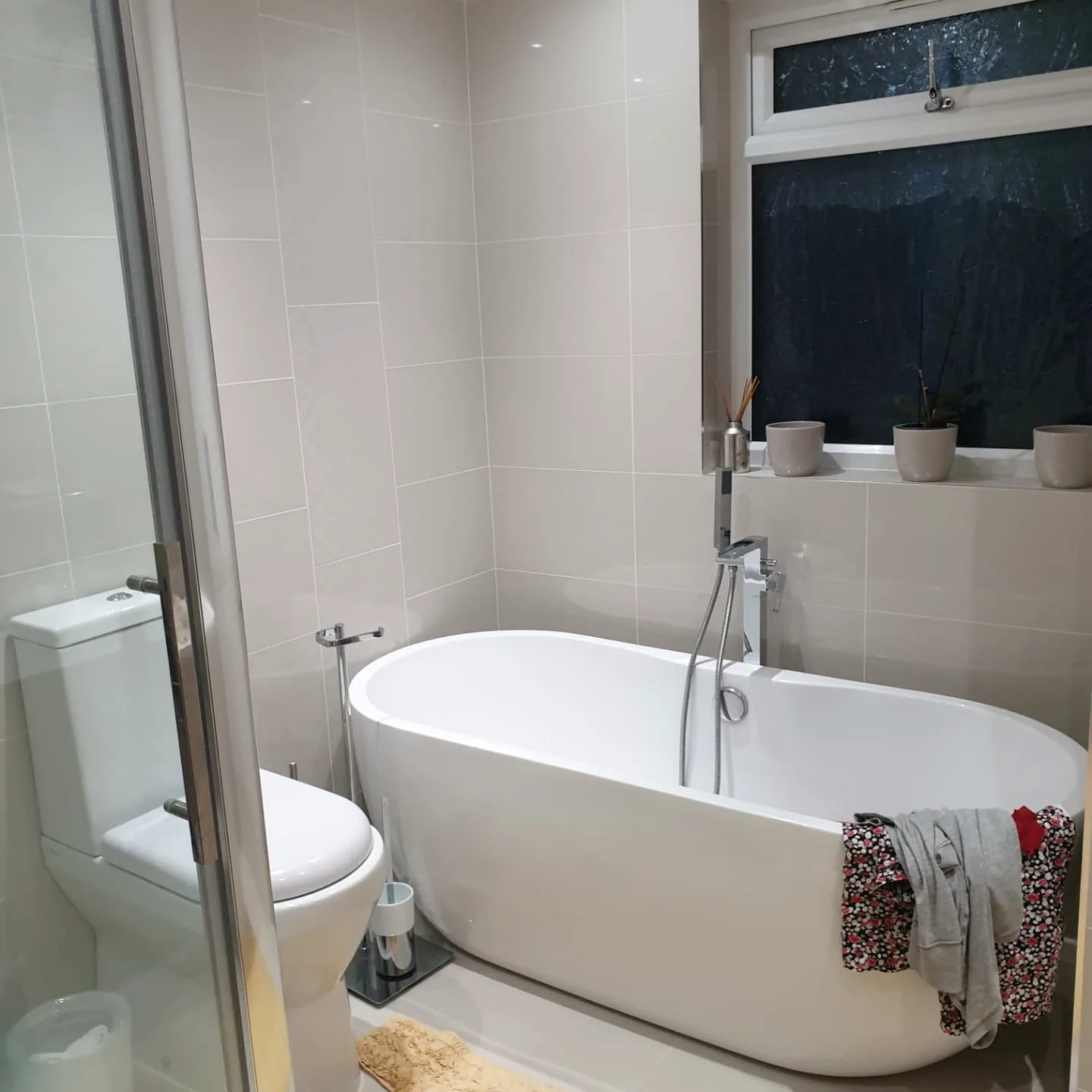 Completed bathroom with freestanding bath, shower screen and neutral tiling