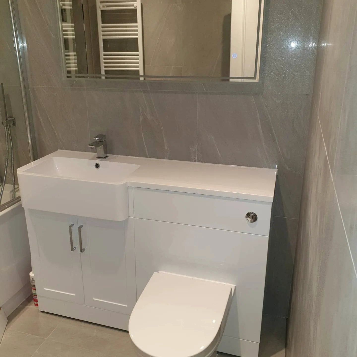Compact bathroom with fitted white vanity unit, toilet and grey wall tiles