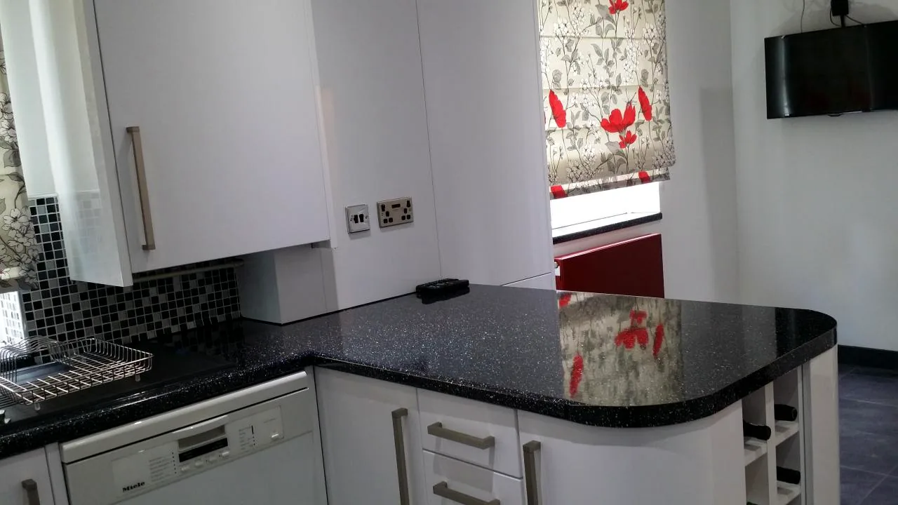 White kitchen cabinets and polished black granite worktop detail