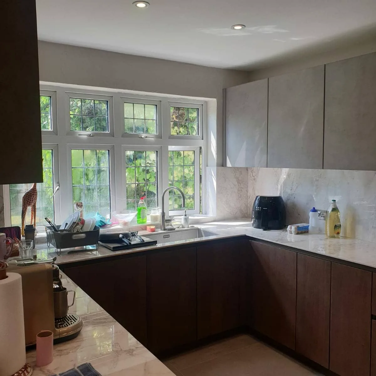 Wood-finish kitchen cabinets and stone worktop fitted around a garden window
