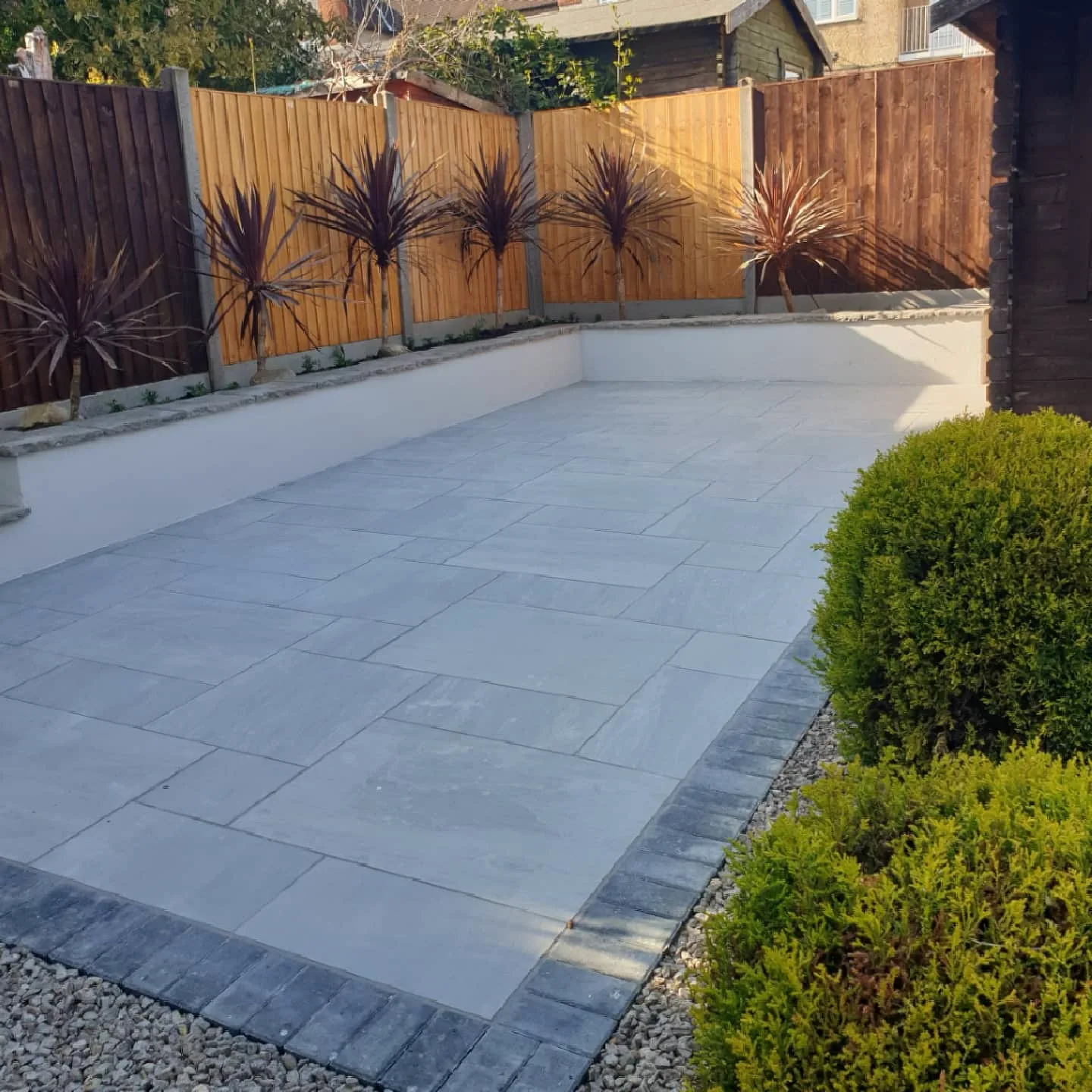 Finished porcelain garden patio with dark edging and rendered raised planting border